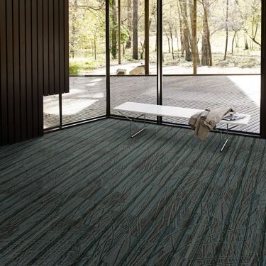 Interface Prairie Grass carpet tile in glass-enclosed room with white bench