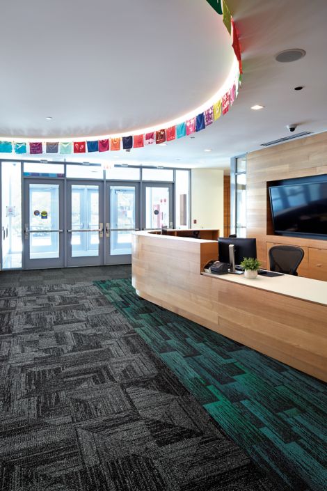 Interface Open Air 403 carpet tile in front desk area with multi color small flags overhead