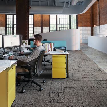 Interface Kerbstone and Sett in Stone carpet tile with Textured Stones LVT in desk area with man working at computer image number 1