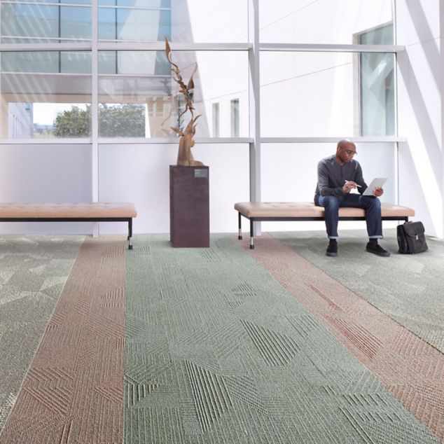 Interface Play the Angle and Spandrel plank carpet tile in seating area with man seated 