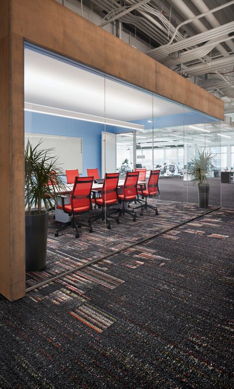 Interface Hard Drive and Static Lines carpet tiles in empty meeting room with glass walls and red chairs
