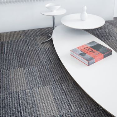Detail of Interface Stroud II carpet tile with white tables of varying sizes