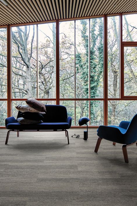 Interface Touch of Timber plank carpet tile in room with floor to ceiling windows, wood ceiling and blue sofa and chair