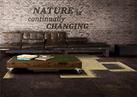 Interface, UR101, UR102 and UR103 carpet tile in seating area with brown sofa, wood coffee table with "grass" top and exposed brick wall