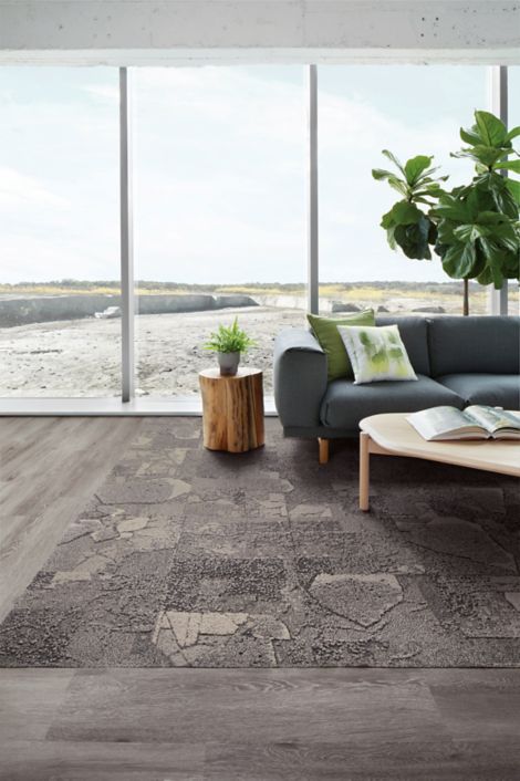 Interface Mountain Rock carpet tile and Textured Woodgrains LVT in seating area with plant on side table and behind couch
