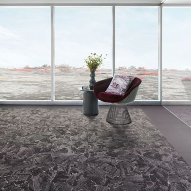 Interface Mile Rock carpet tile and Brushed Lines LVT in open room with chair and side table with plant