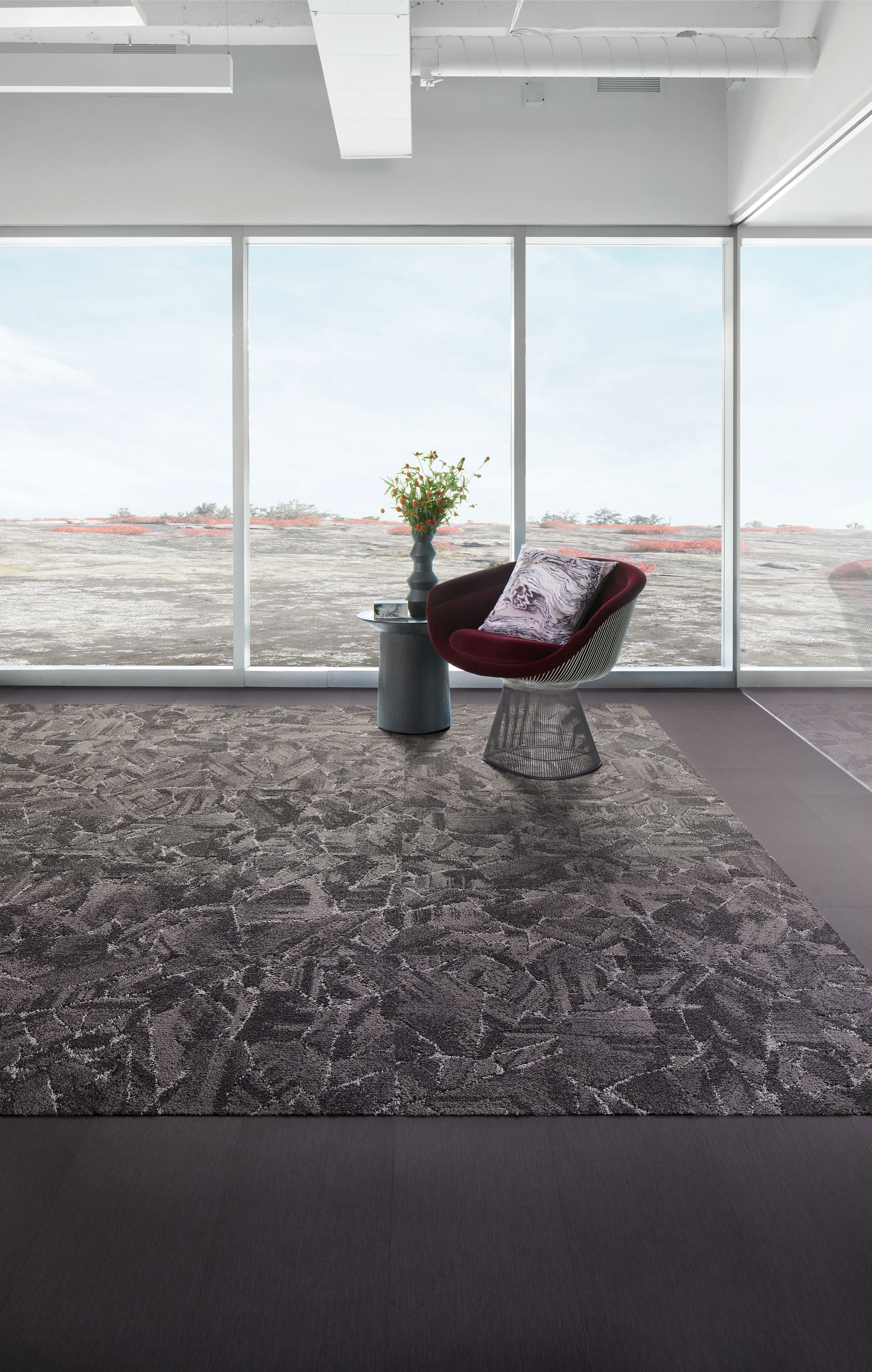 Interface Mile Rock carpet tile and Brushed Lines LVT in open room with chair and side table with plant image number 1