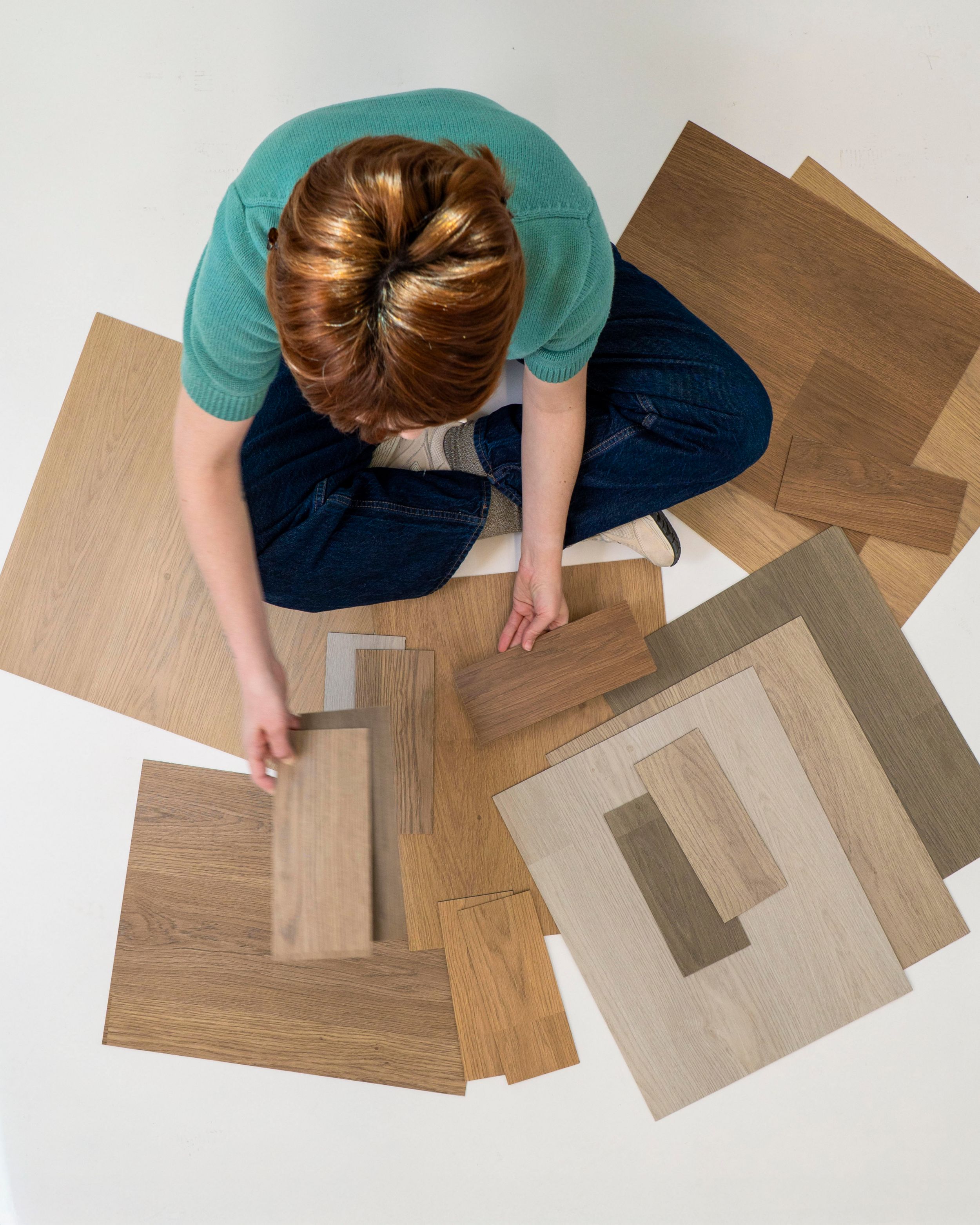 woman sitting cross-legged looking at different color samples of noravant timber rubber flooring num&eacute;ro d&rsquo;image 16