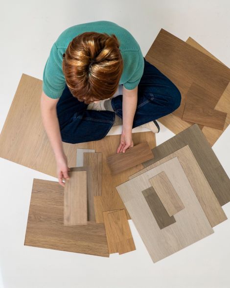 woman sitting cross-legged looking at different color samples of noravant timber rubber flooring num&eacute;ro d&rsquo;image 16