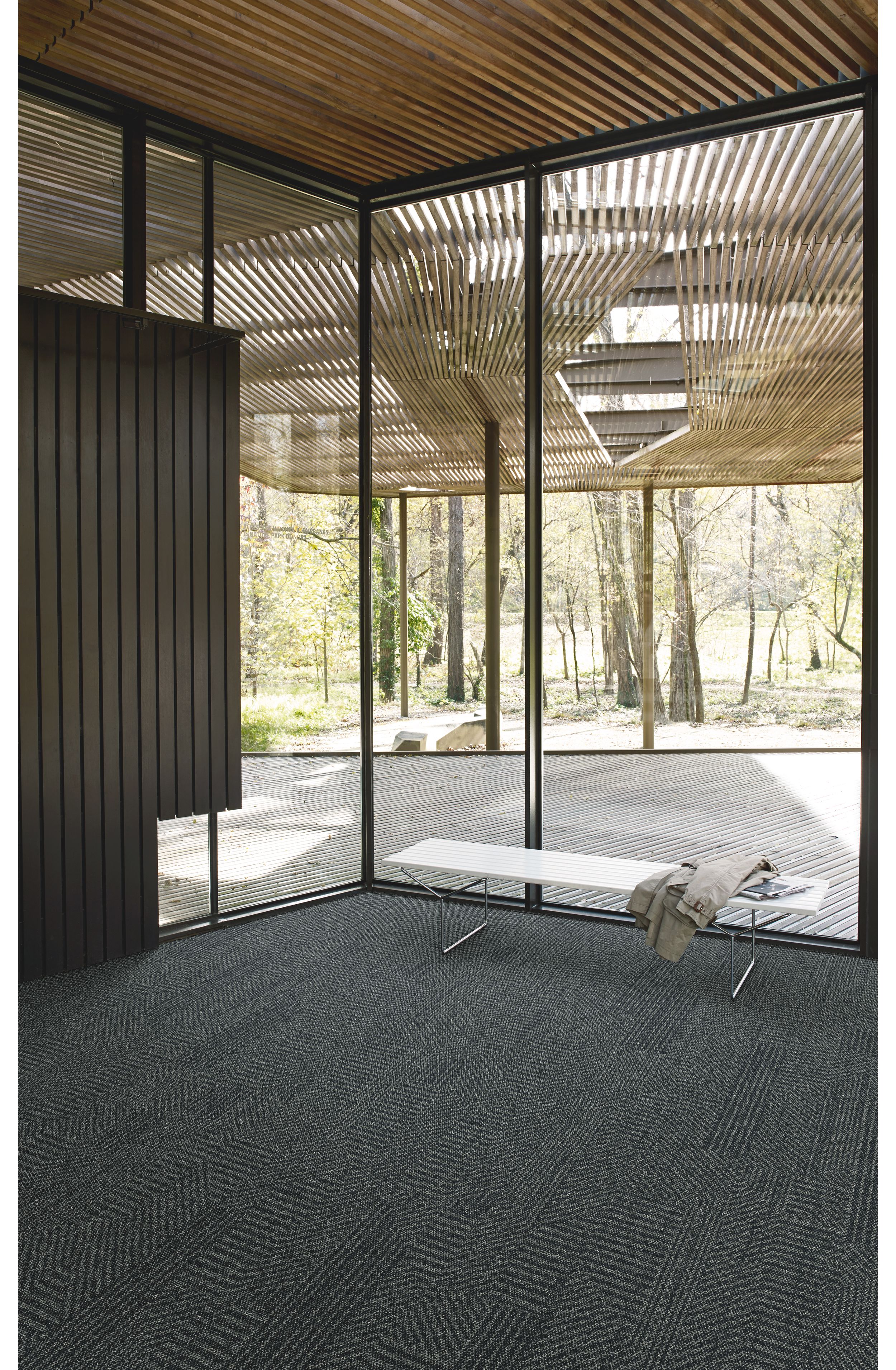 Interface Open Air 407 plank carpet tile in corner space with jacket draped over small white bench and wood slat ceiling image number 5