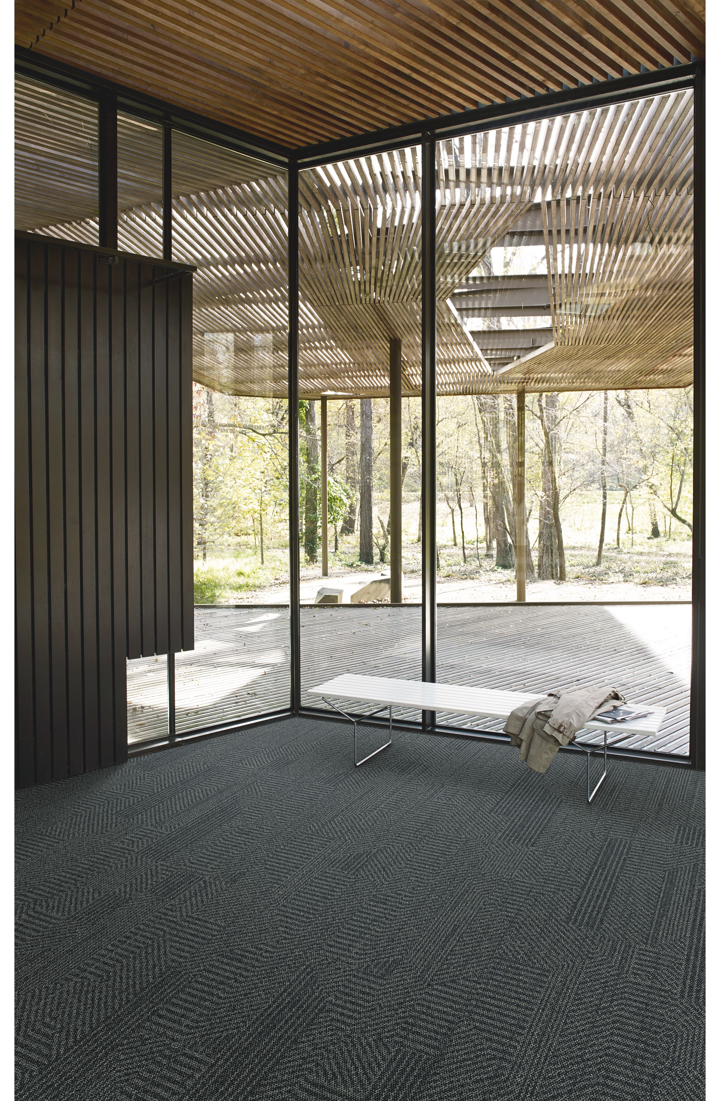 Interface Open Air 407 plank carpet tile in corner space with jacket draped over small white bench and wood slat ceiling imagen número 5