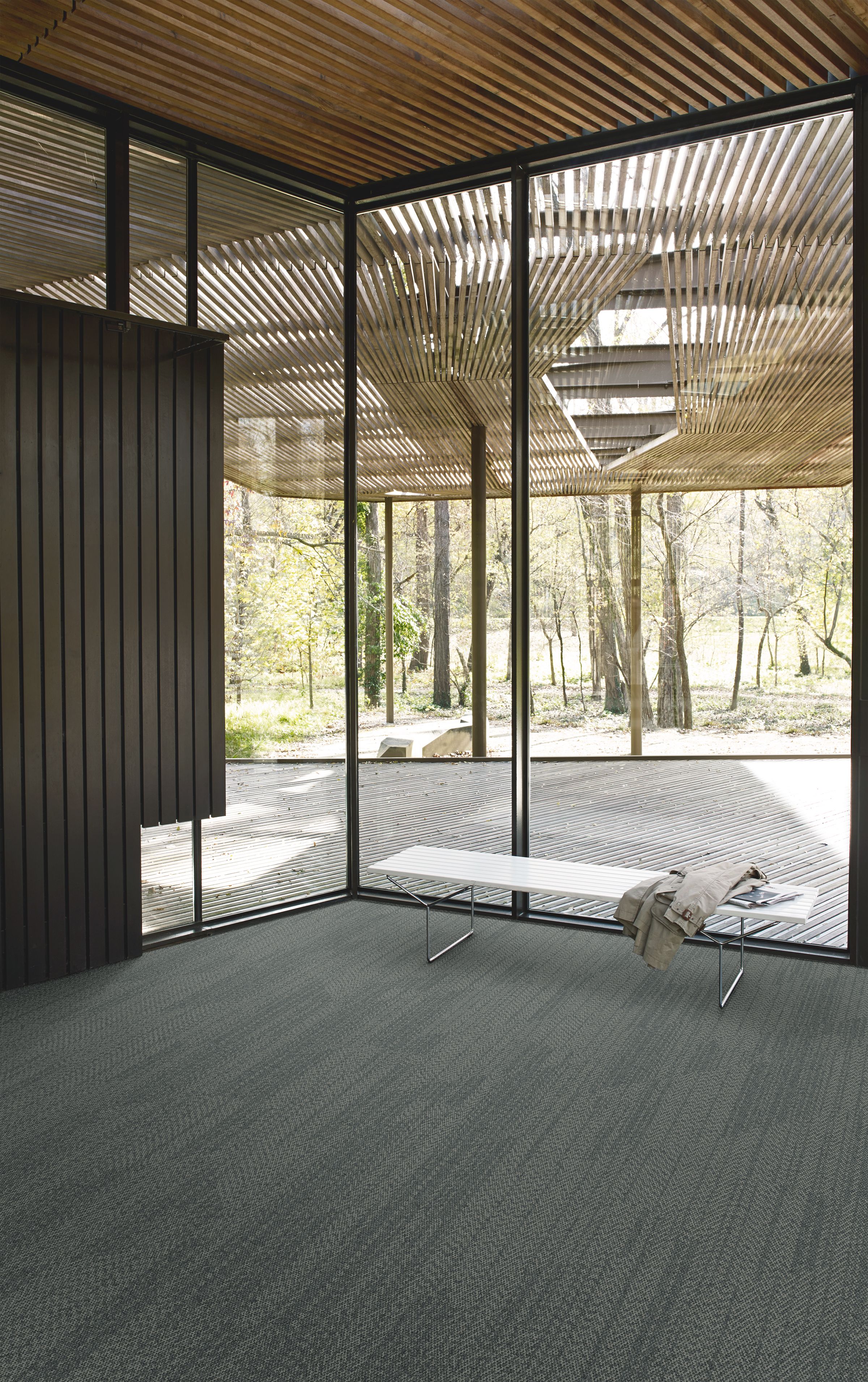 Interface Open Air 408 plank carpet tile in corner space with jacket draped over small white bench and wood slat ceiling numéro d’image 8