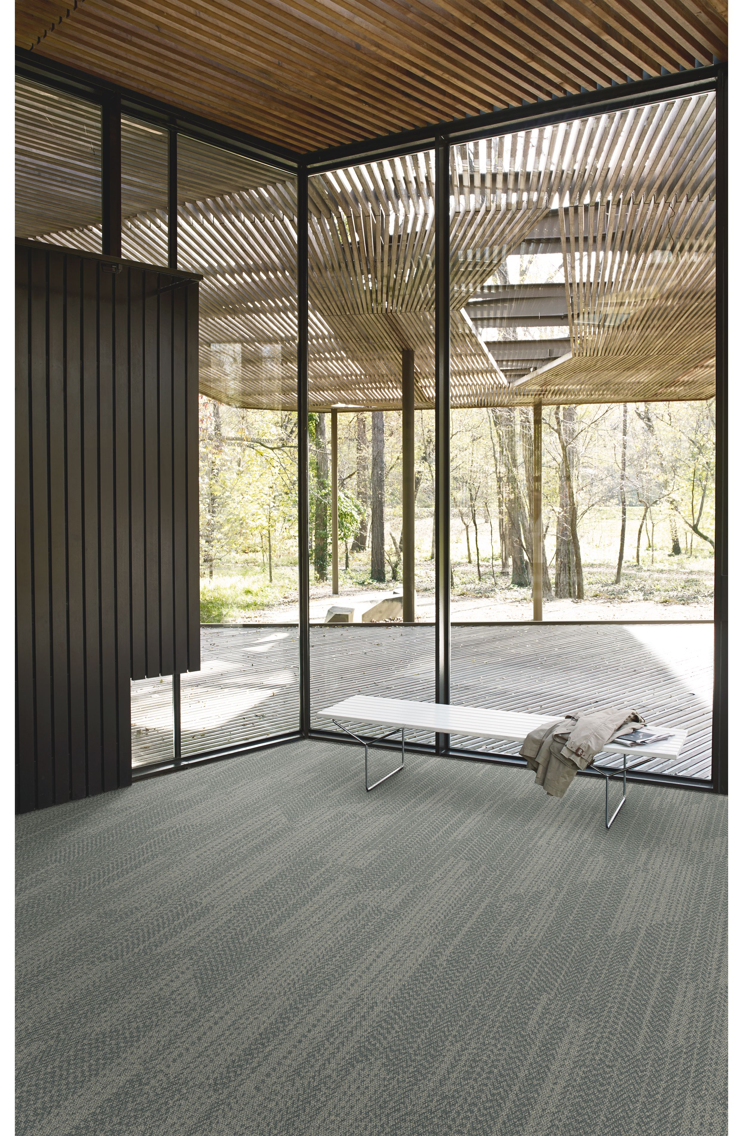 Interface Open Air 408 plank carpet tile in corner space with jacket draped over small white bench and wood slat ceiling imagen número 1