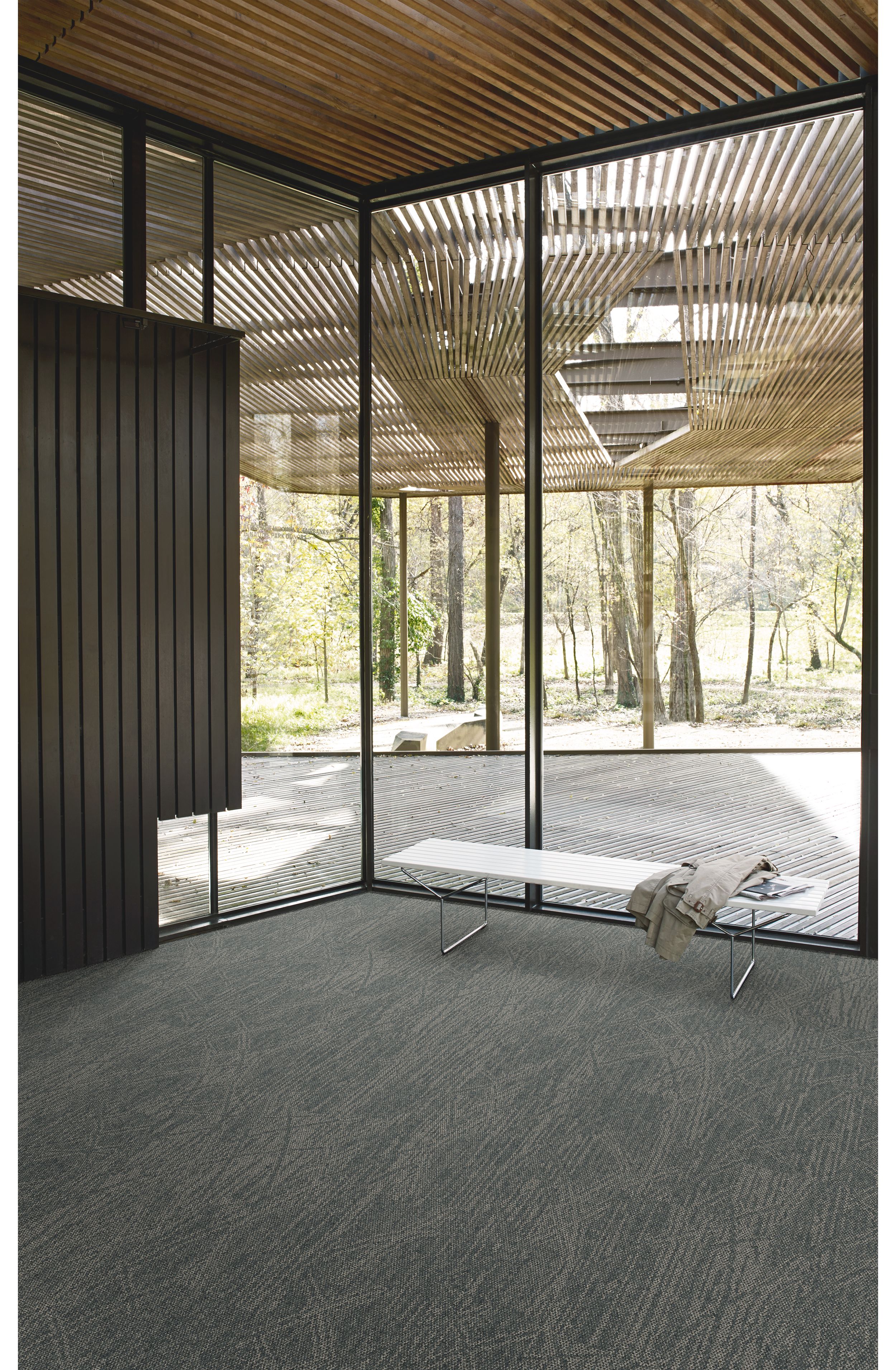 Interface Open Air 409 plank carpet tile in corner space with jacket draped over small white bench and wood slat ceiling image number 3