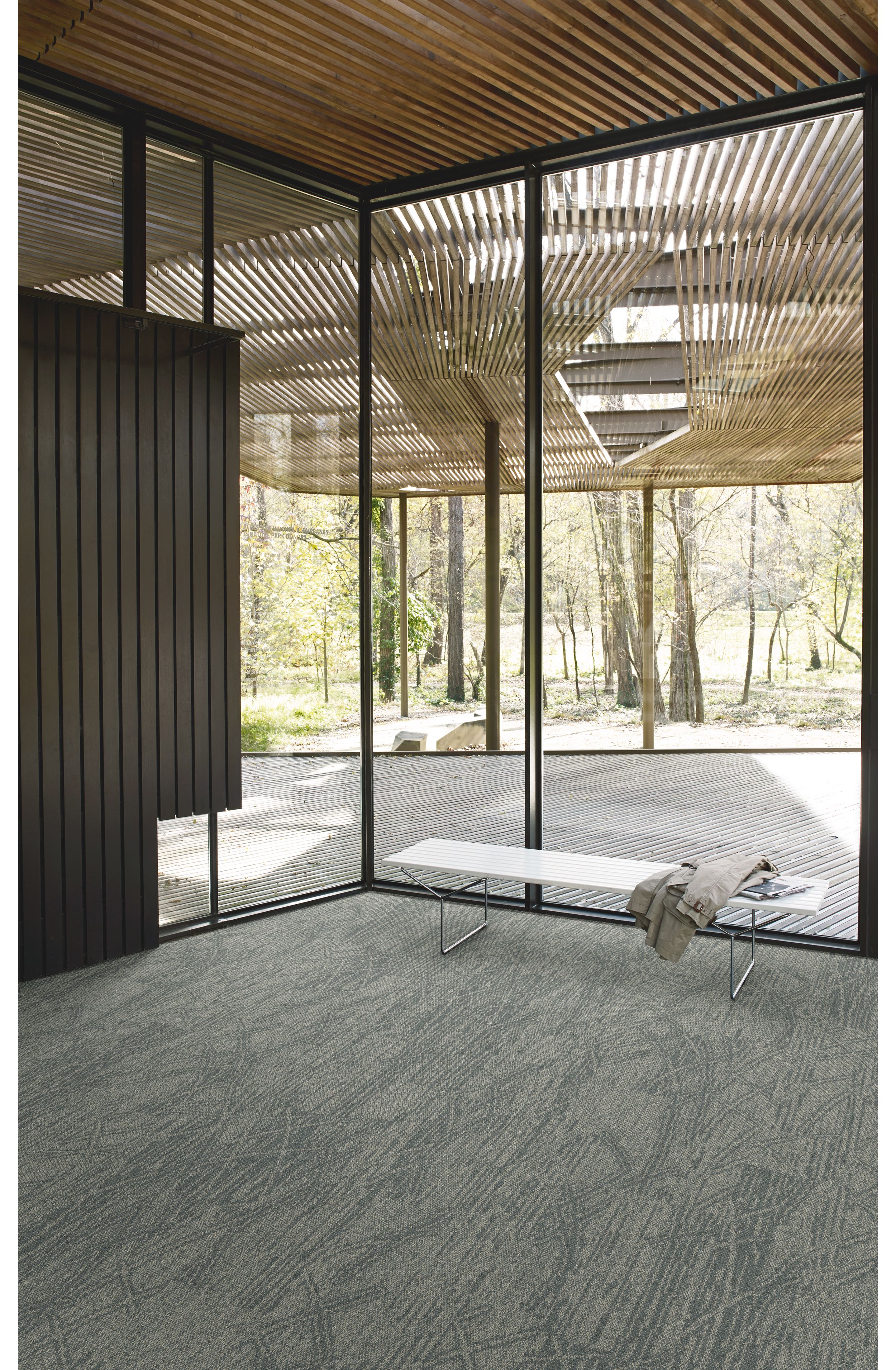 Interface Open Air 409 plank carpet tile in corner space with jacket draped over small white bench and wood slat ceiling image number 2