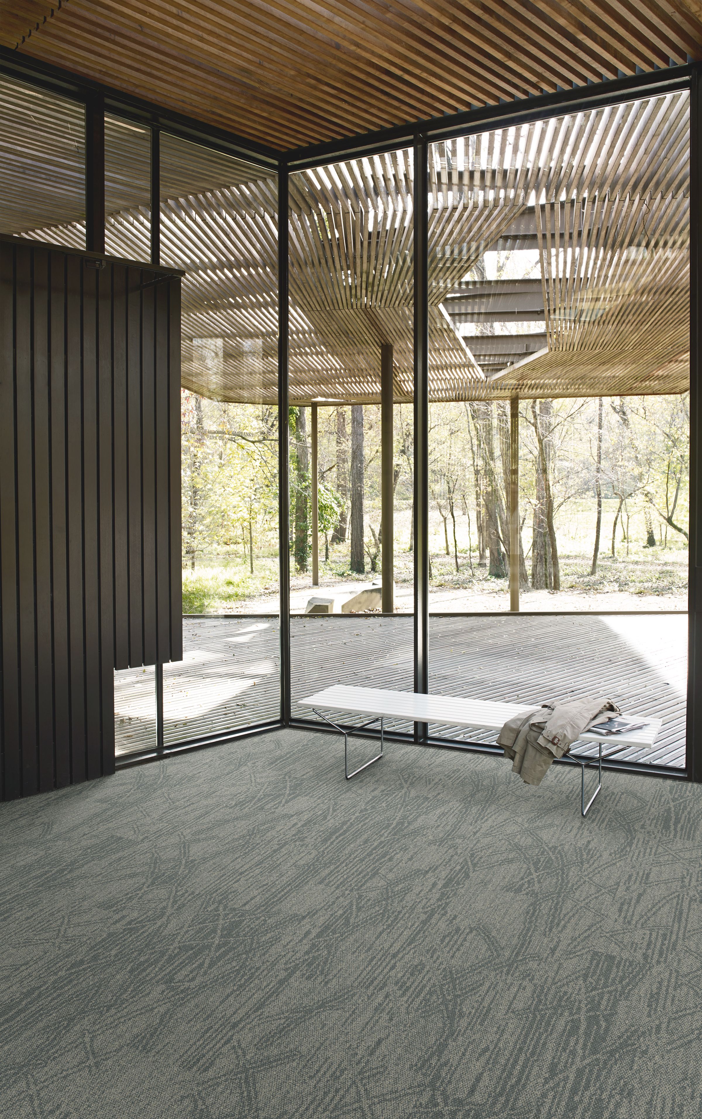 Interface Open Air 409 plank carpet tile in corner space with jacket draped over small white bench and wood slat ceiling imagen número 6