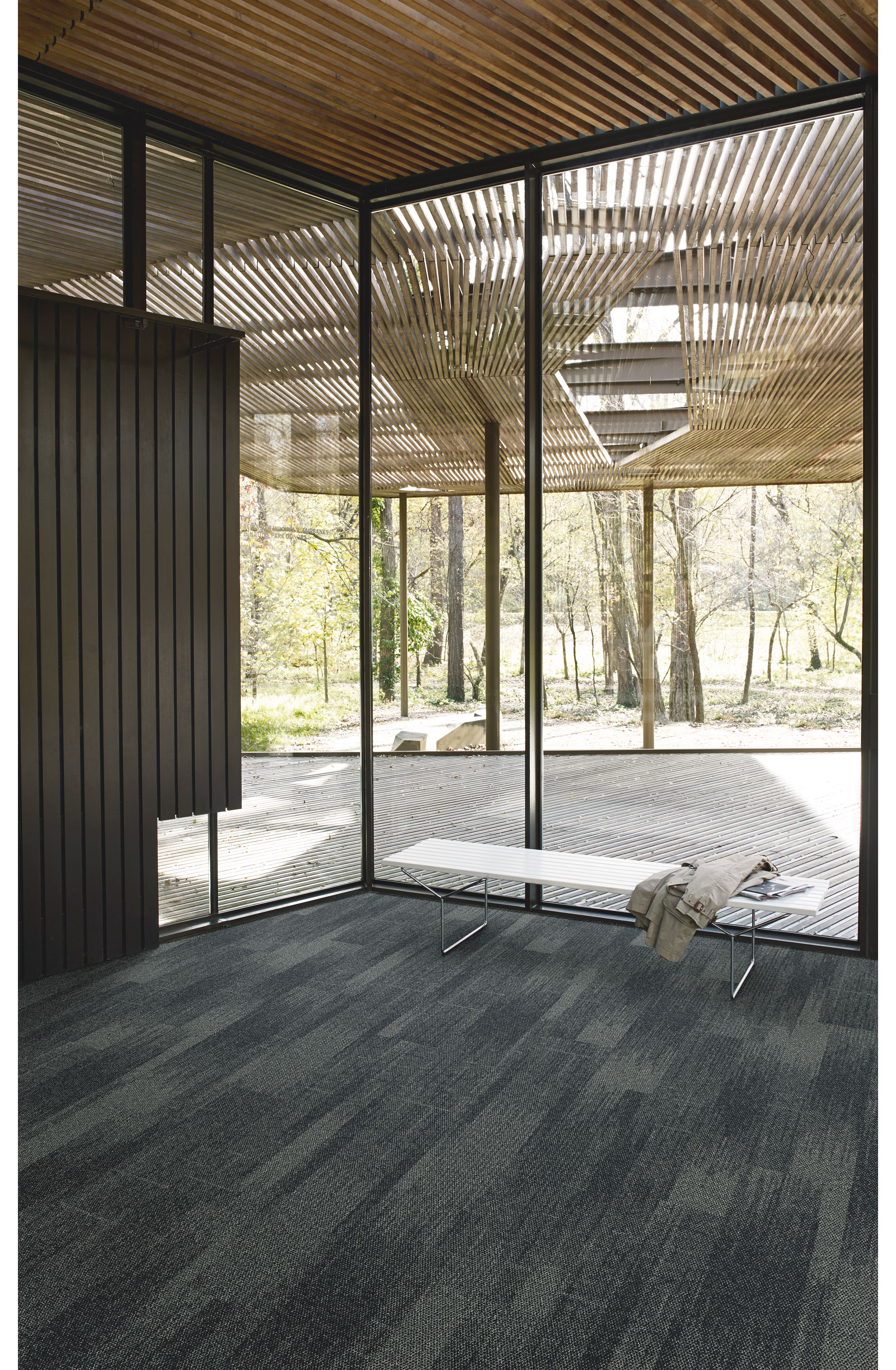 Interface Open Air 410 plank carpet tile in corner space with small white bench and wood slat ceiling image number 4