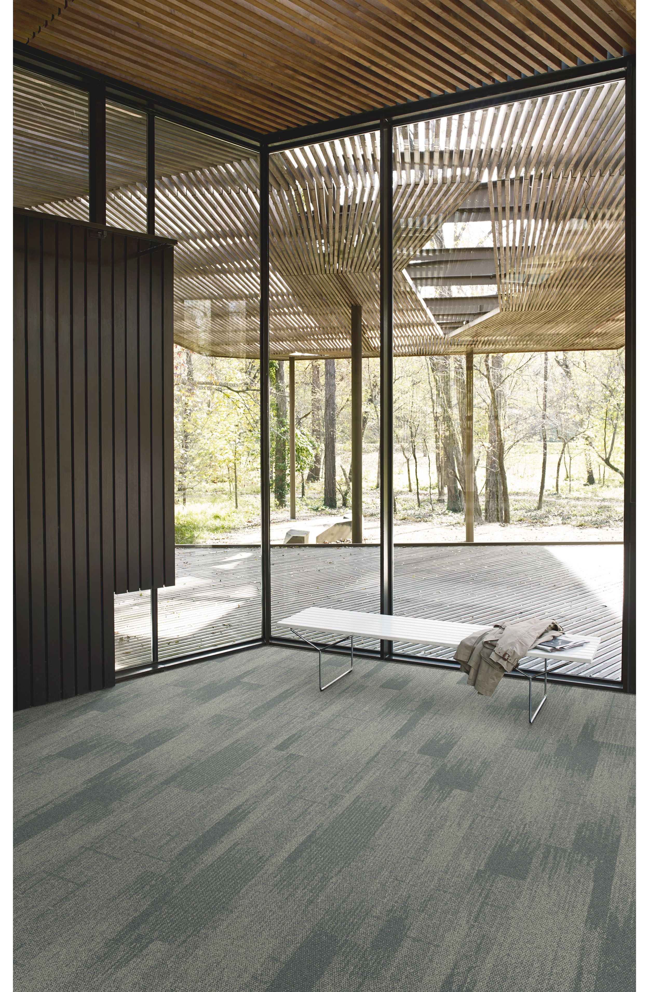 Interface Open Air 410 plank carpet tile in corner space with small white bench and wood slat ceiling imagen número 3