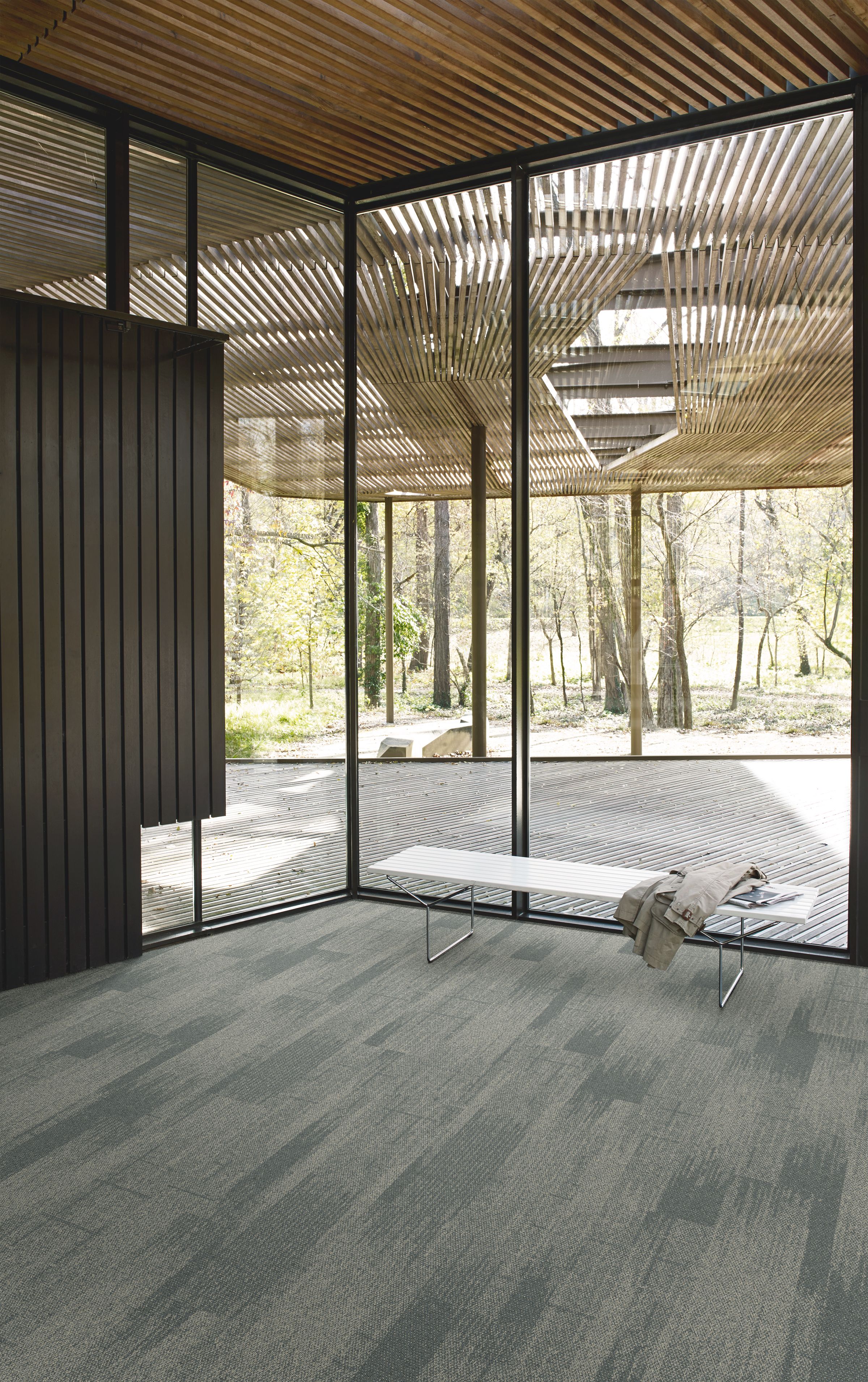 Interface Open Air 410 plank carpet tile in corner space with small white bench and wood slat ceiling imagen número 3
