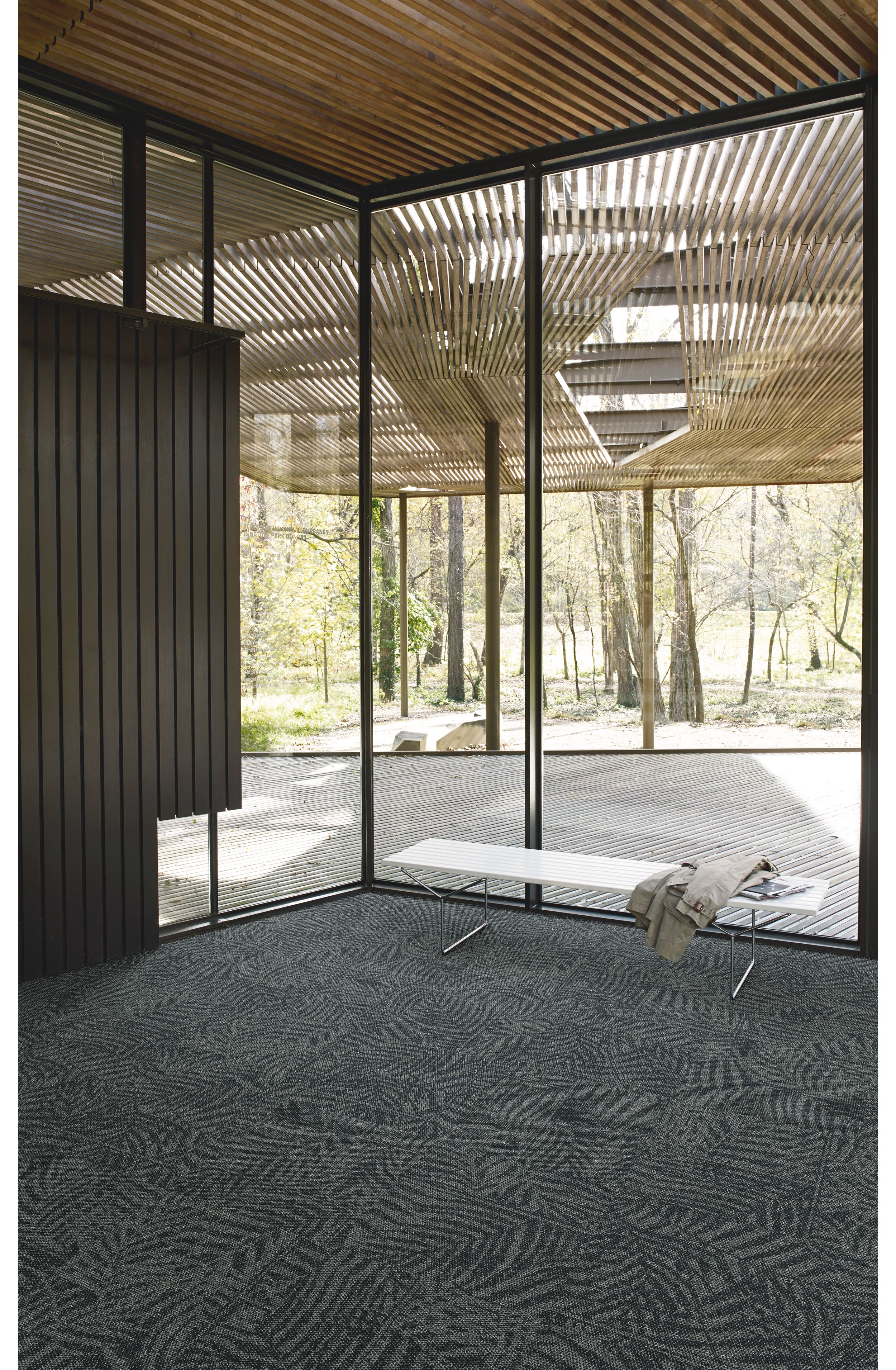 Interface Open Air 422 carpet tile in corner space with jacket draped over small white bench and wooden slat ceiling image number 2