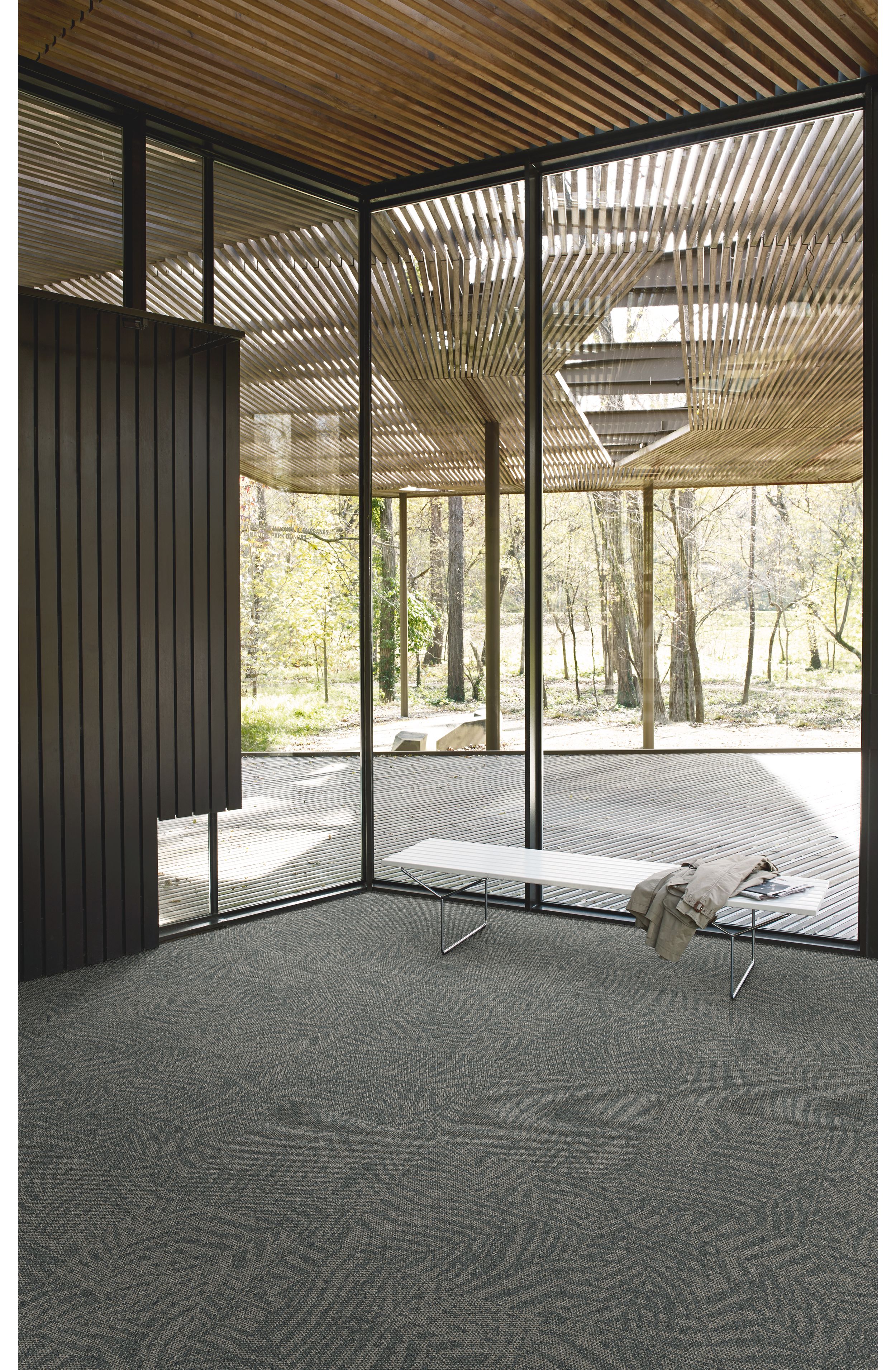 Interface Open Air 422 carpet tile in corner space with jacket draped over small white bench and wooden slat ceiling image number 4