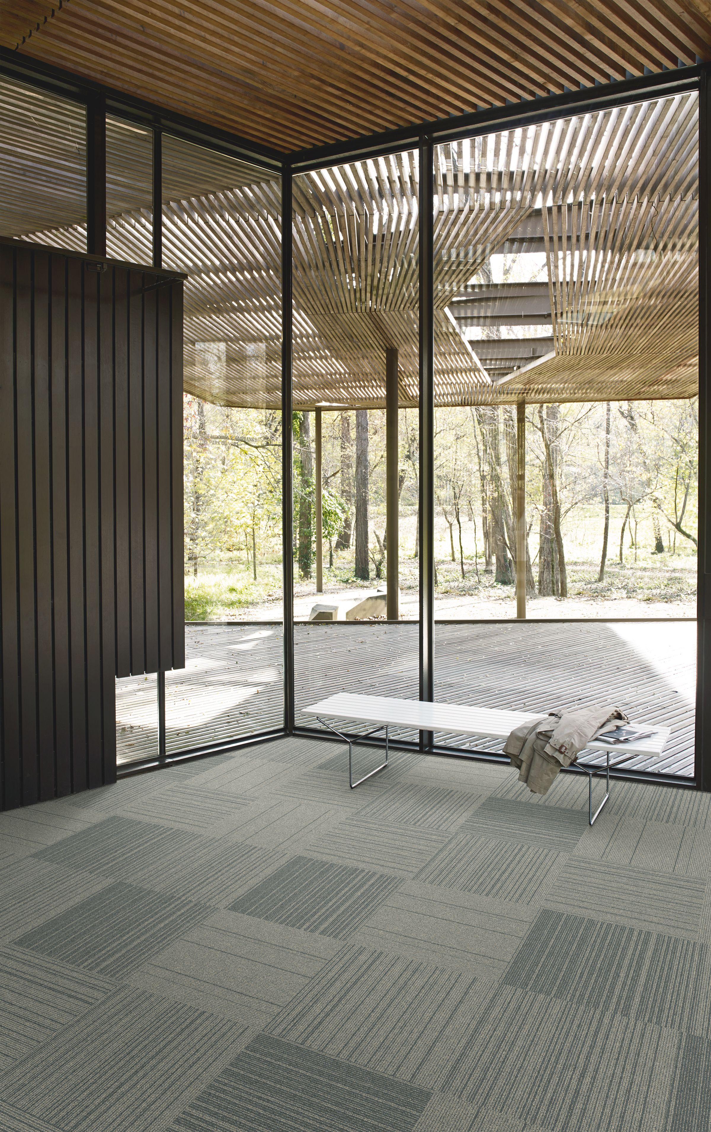 Interface Open Air 423 carpet tile in corner space with small white bench and wooden slat ceiling imagen número 3