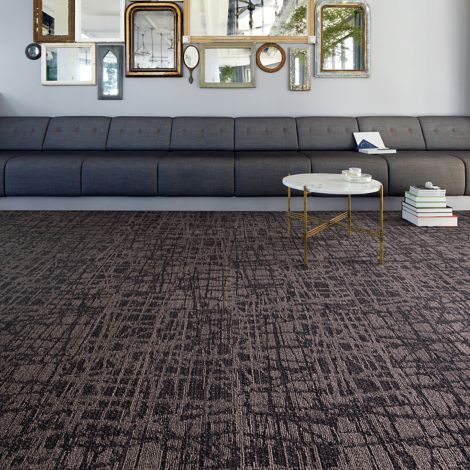 Interface WE153 plank carpet tile in lobby area with long couch, small white table and arrangement of mirrors on wall