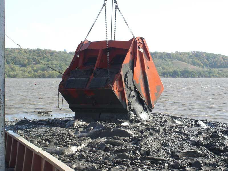 Crane dumping mud ini a back of a truck