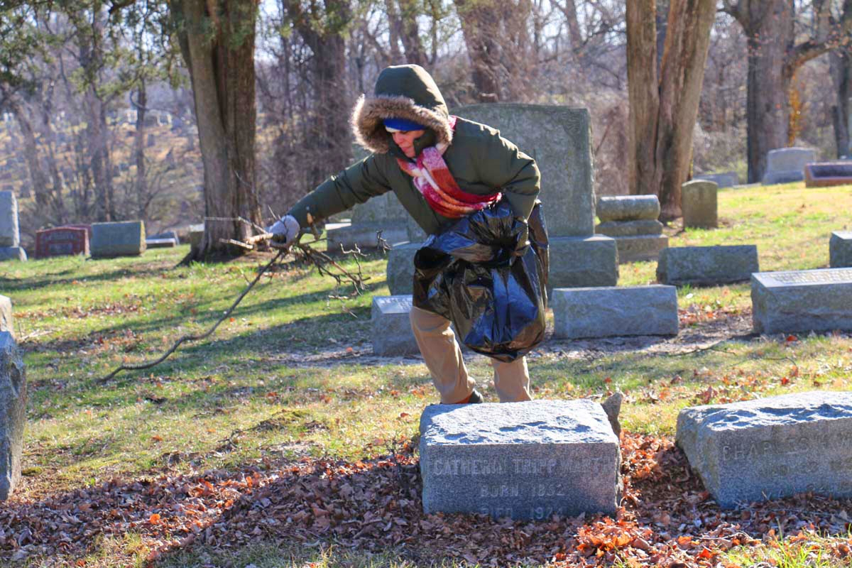 Volunteer picking up sticks in a cemetary