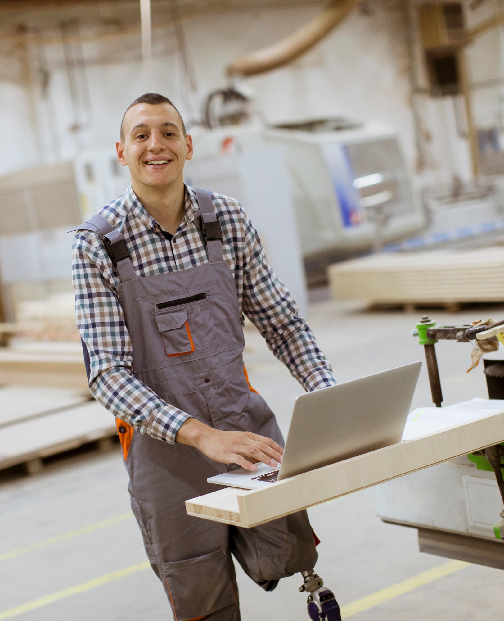 Disabled young man with an prosthesis is working at the furniture factory