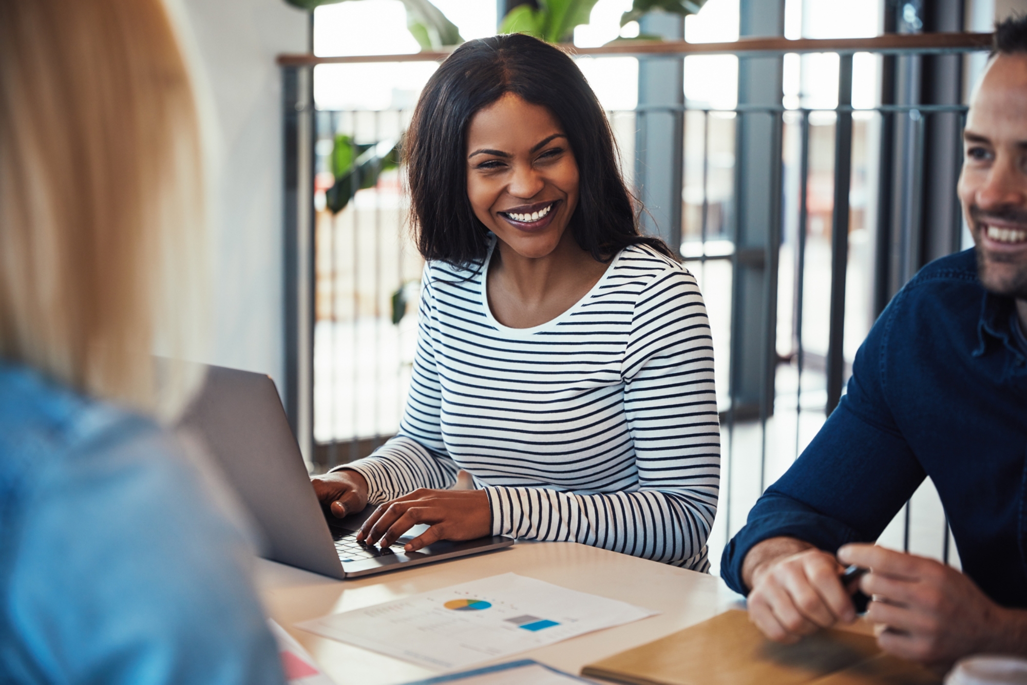 Young African American businesswoman laughing with a group of diverse coworkers during a meeting together around an office table