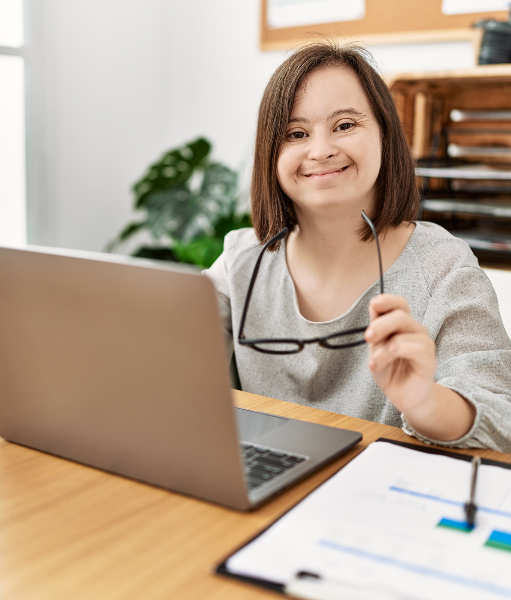 Brunette woman with down syndrome working using laptop at business office