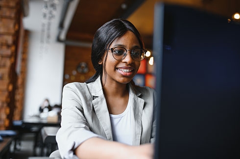 Focused young african american businesswoman or student looking at laptop, serious black woman working or studying with computer doing research or preparing for exam online