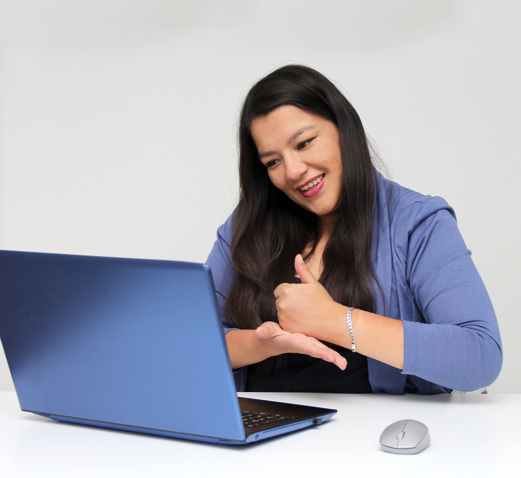 Latino adult woman speaks Mexican sign language with a deaf person through a laptop in a video call