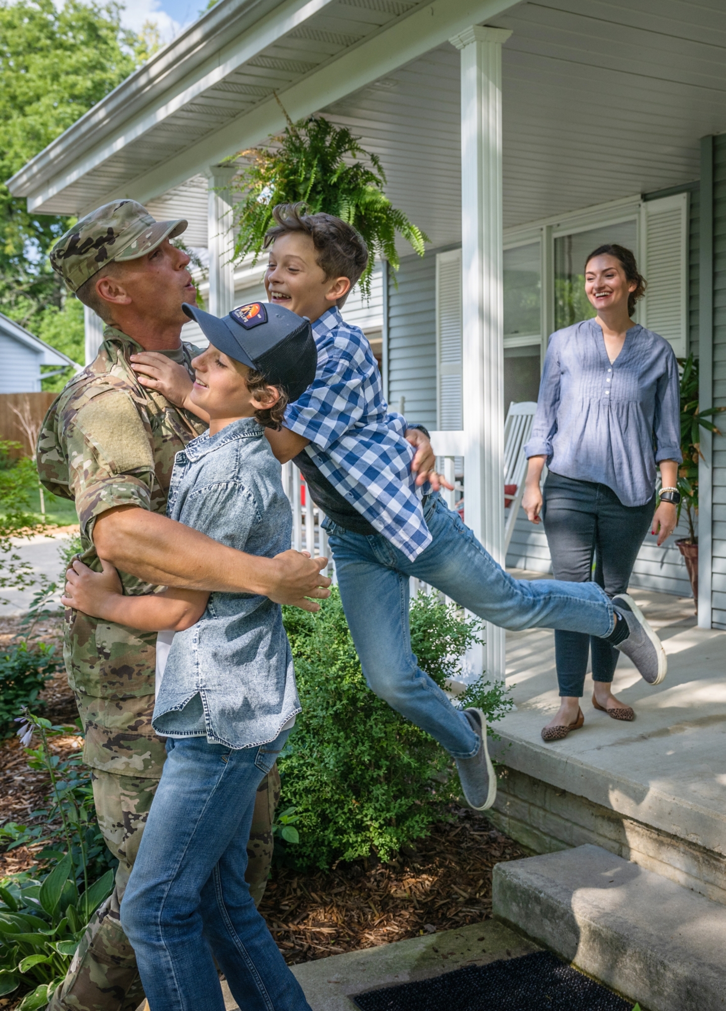 Air Force service member comes home to his family and  veteran father-in-law on the front porch.