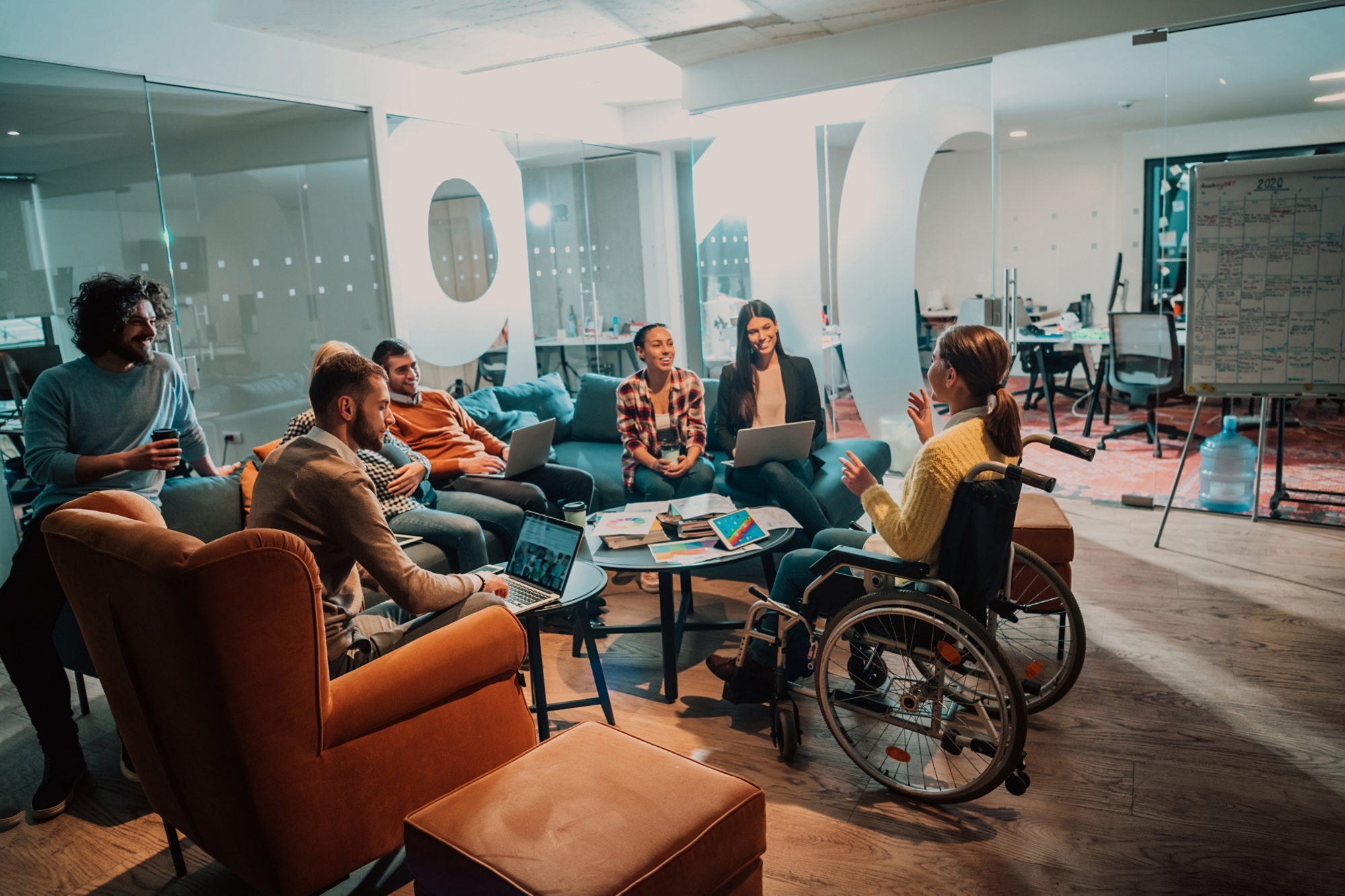 A businesswoman in a wheelchair having a business meeting with the team at a modern office. A group of young freelancers agree on new online business projects. 