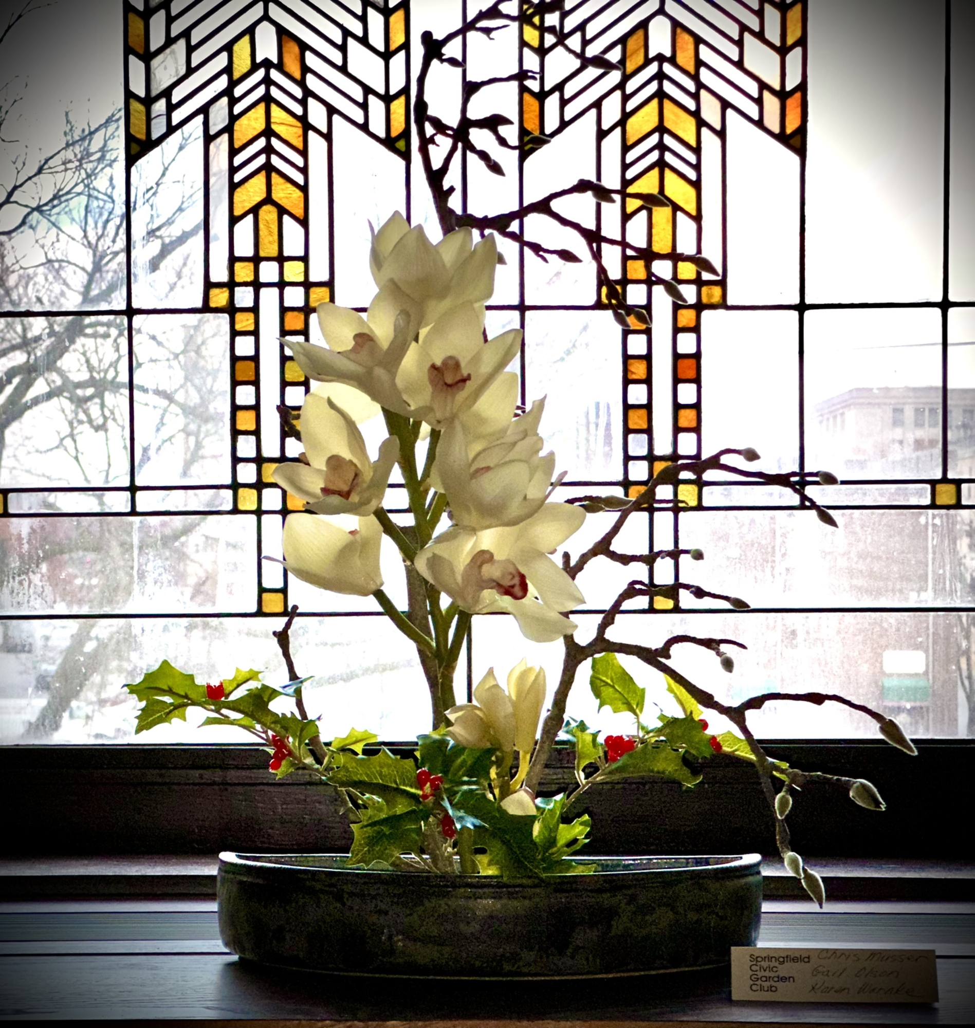 Floral arrangement in a pot in front of a stained glass window