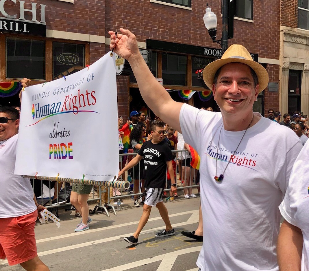 Photo of Jim Bennett carrying an IDHR banner in a parade