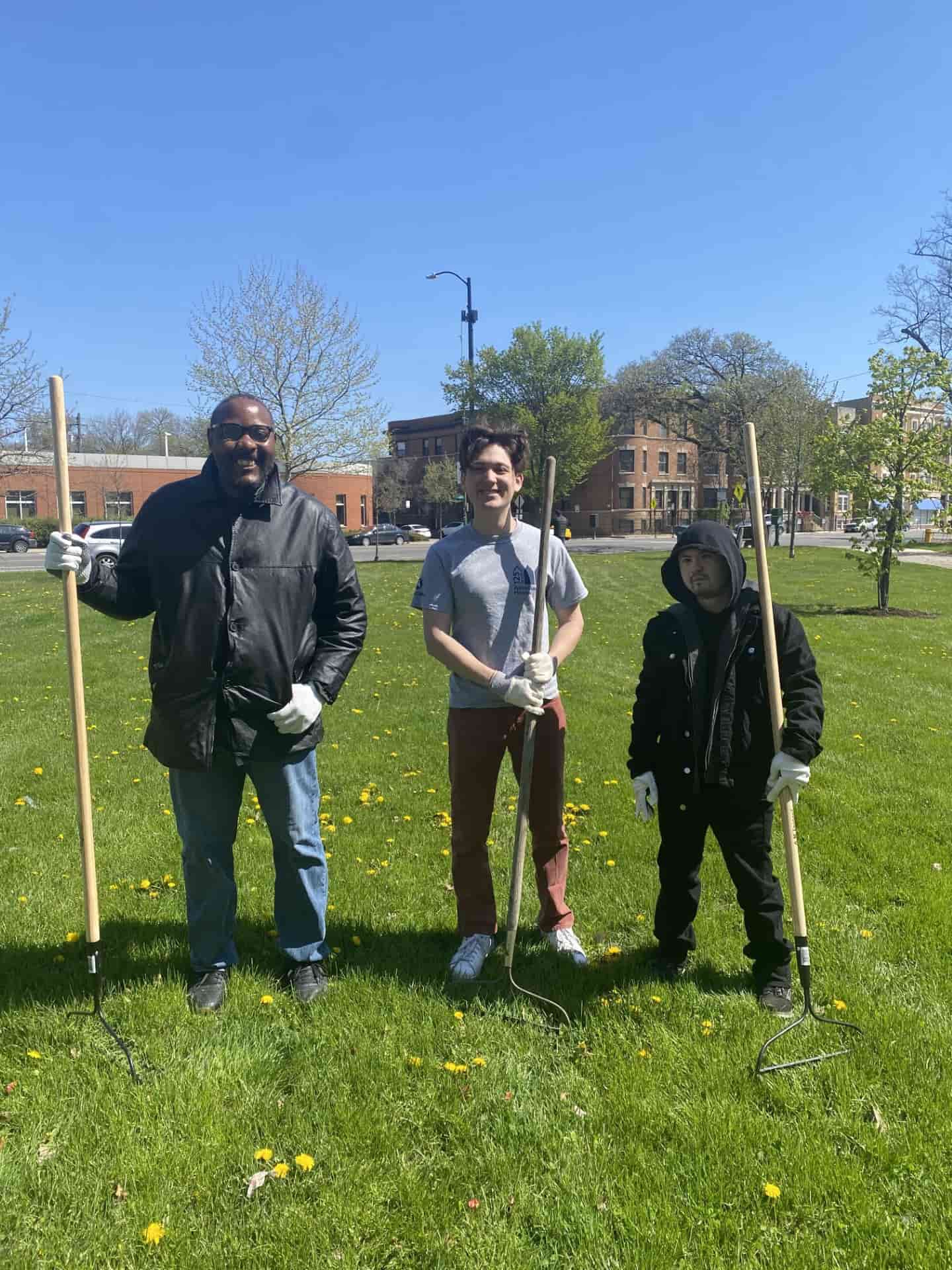 Association House members volunteering on Earth Day. Members are holding gardening tools.