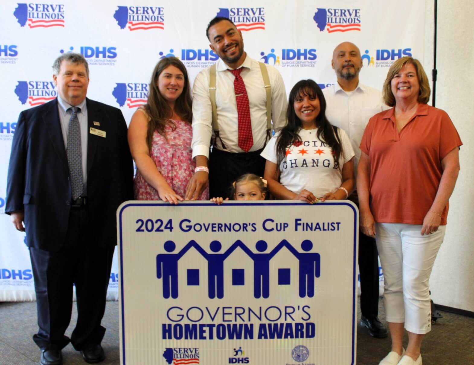 Group photo of representatives of Social Change with Serve Illinois Commissioners and Executive Director Andres Fernandez with Governr's Cup Finalist sign