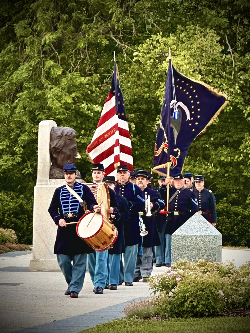 Civil War reenactors in uniform march in front of the Lincoln Tomb with a drum and flags