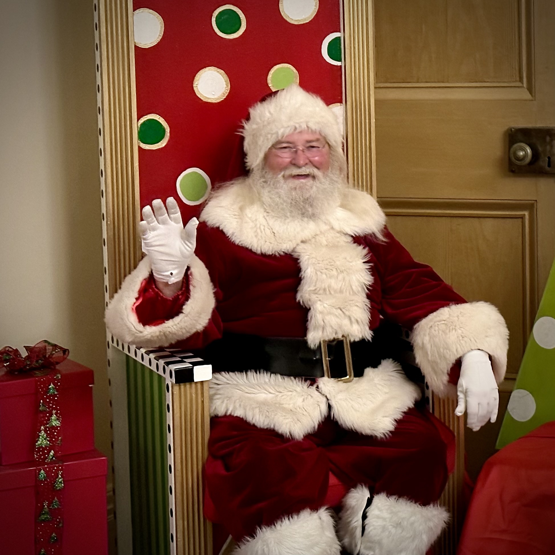 Santa Claus sitting in a chair and waving