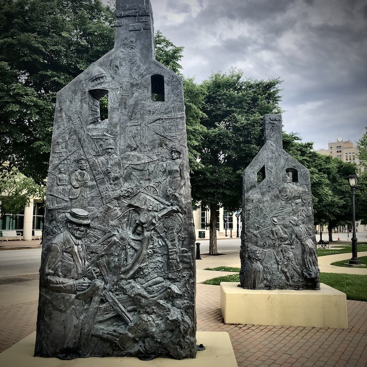 Two house-shaped sculptures with carved images depicting events of the 1908 Springfield Race Riot. Sculpture title is "Acts of Intolerance," artist is Preston Jackson