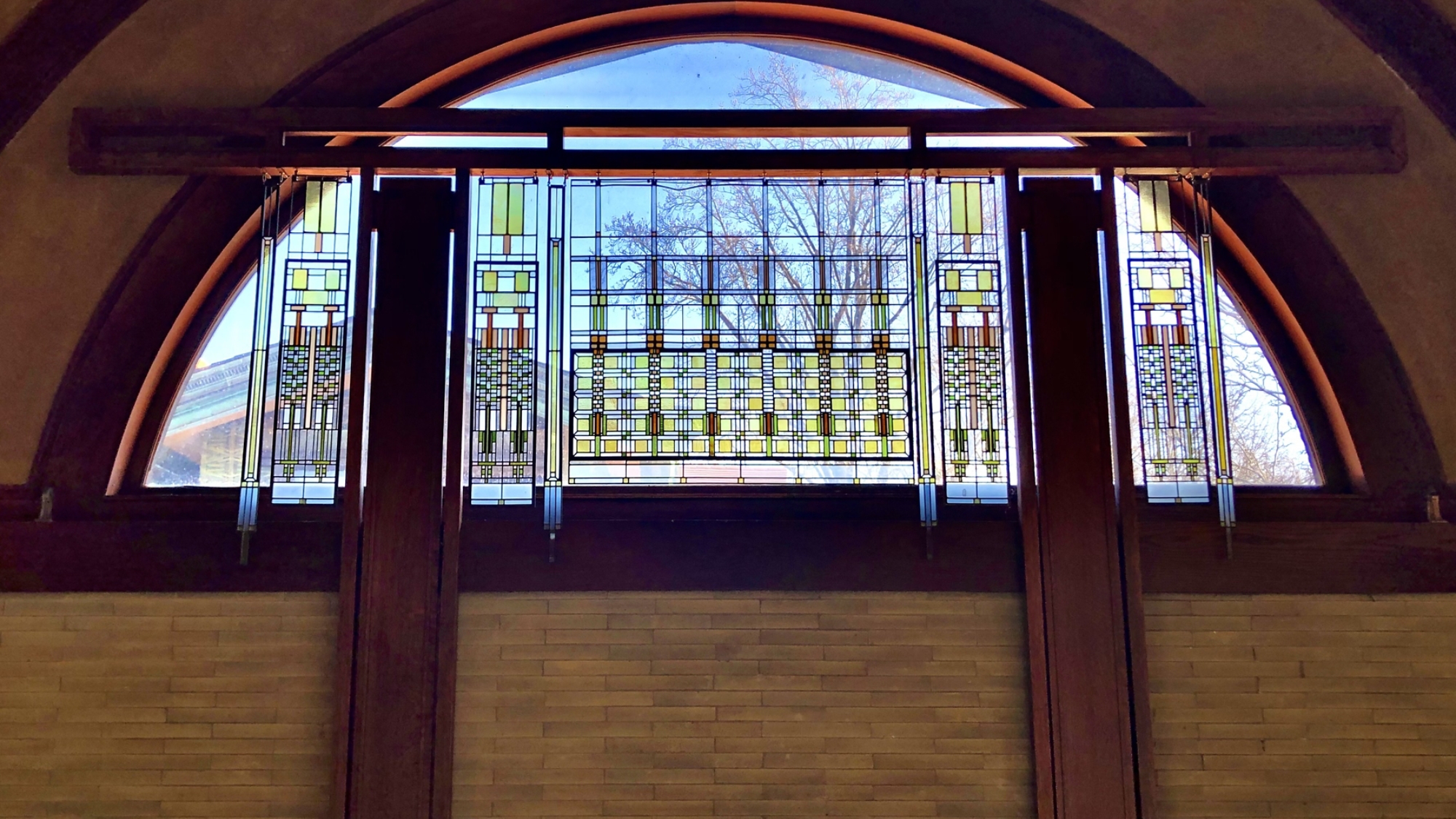 panels of art glass hang from a wooden frame in front of a window