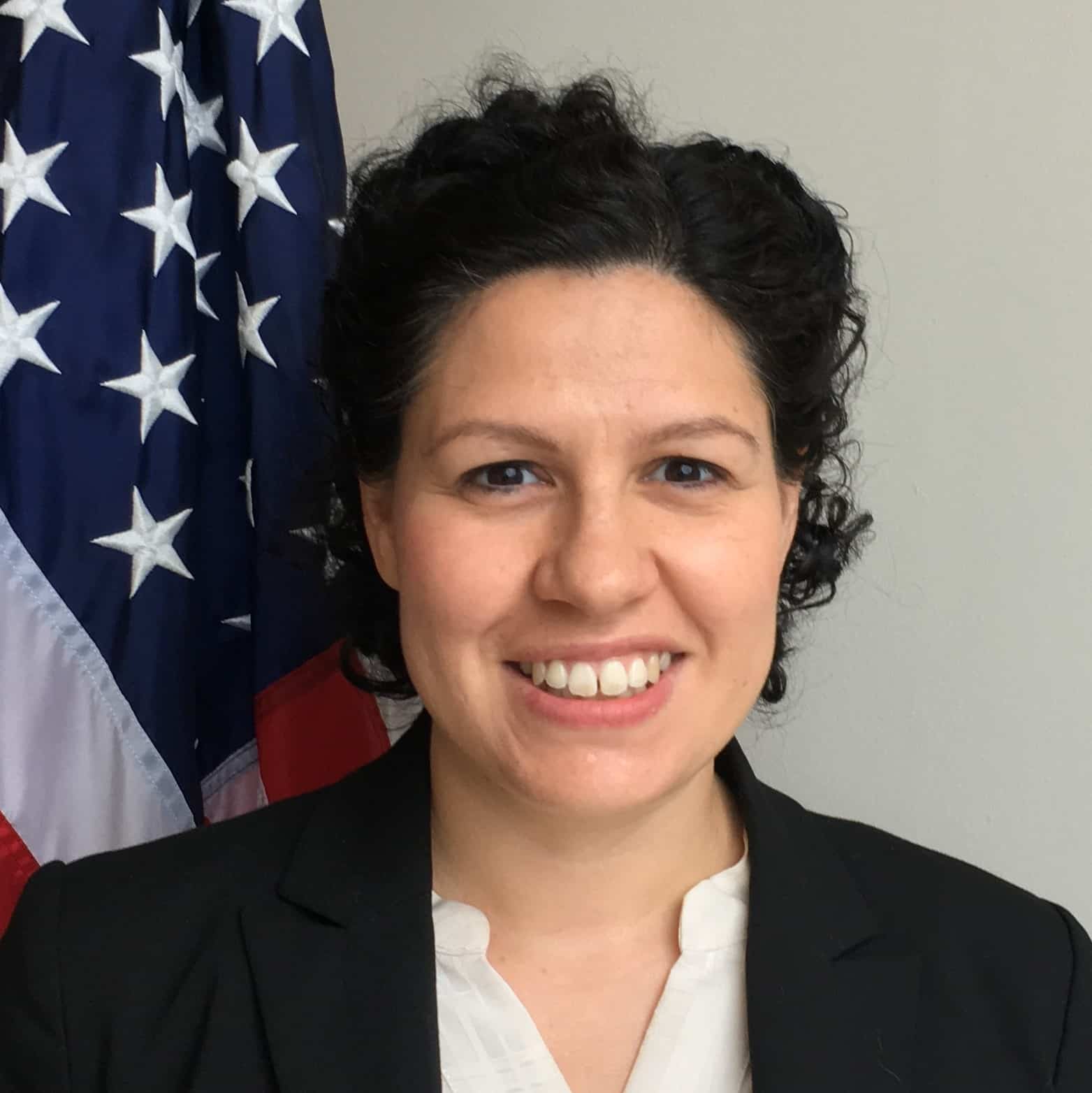 Christine Benavente standing in front of an American flag .