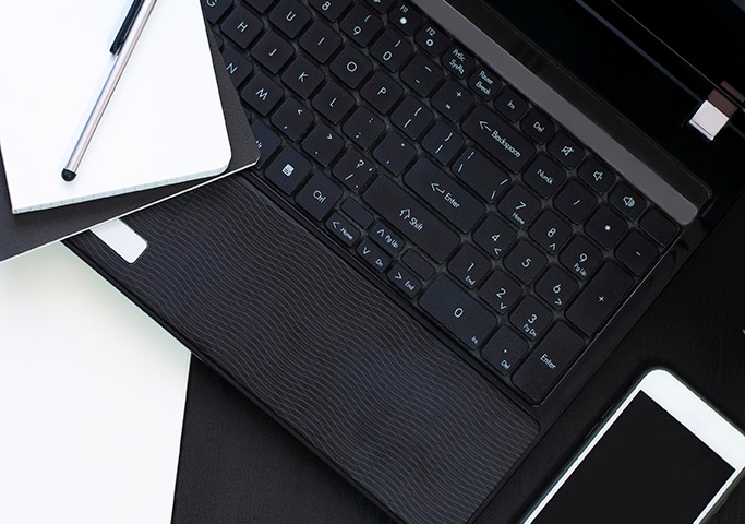 Black and white business background with open laptop, notebook, silver pen, green plant and phone