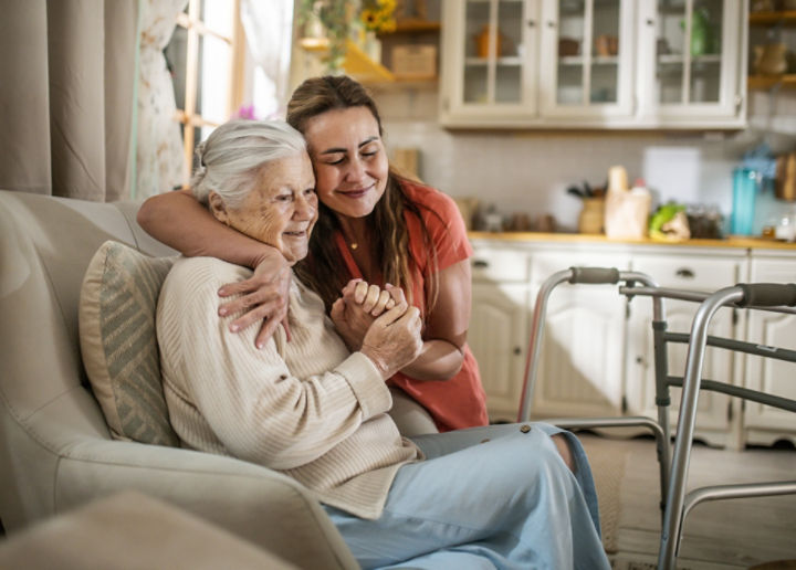 female caregiver embracing senior female in the home