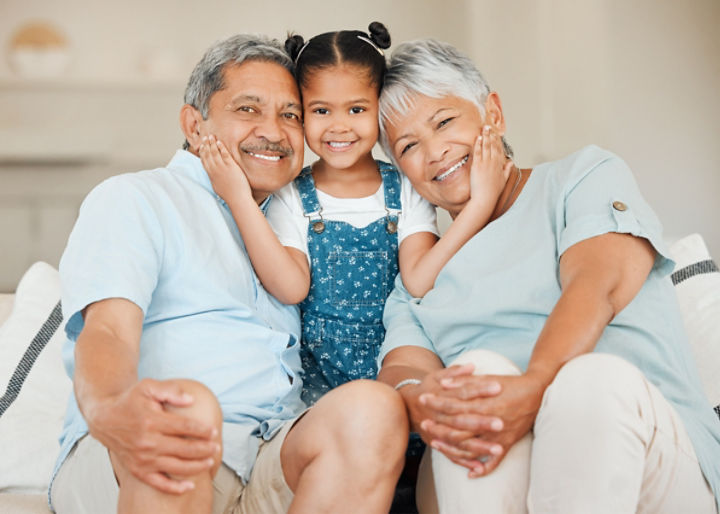 Love, portrait of grandparents with child smile and on a sofa in living room of their home.