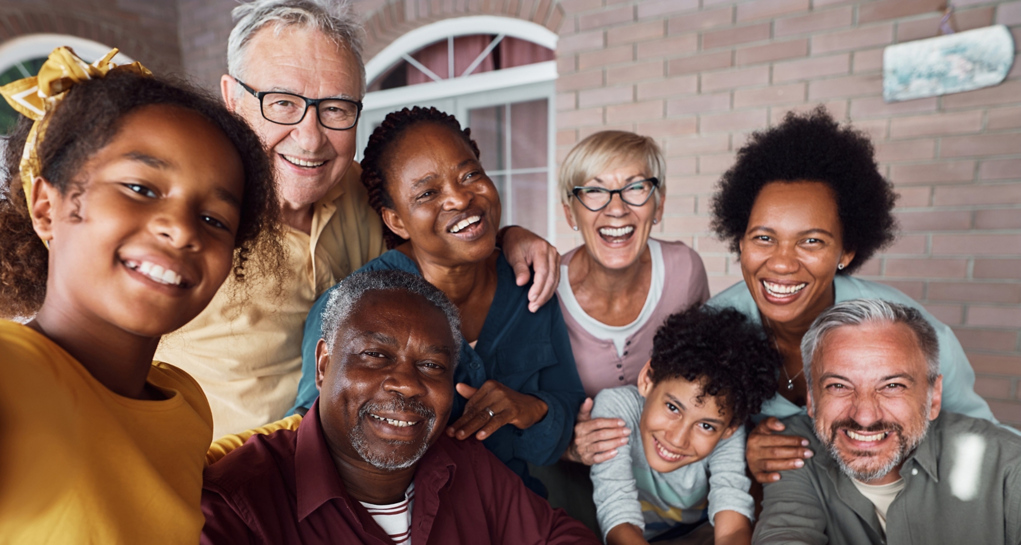 Happy multiracial extended family having fun while taking selfie on patio.