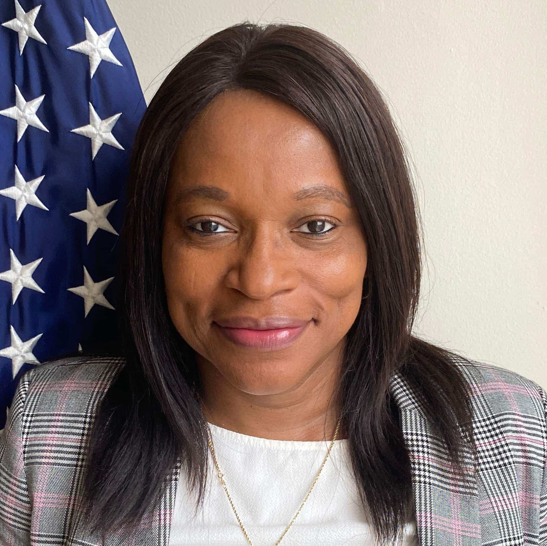 Ogo Akpan standing in front of an American flag .